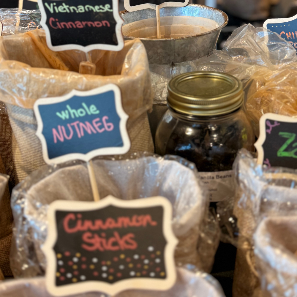 Spice bags labeled Whole Nutmeg and Cinnamon Sticks at a flavor blending station