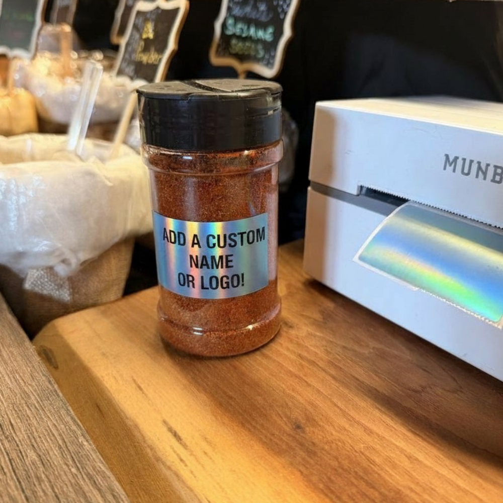 Custom spice jar with a holographic label reading Add a custom name or logo next to a label printer
