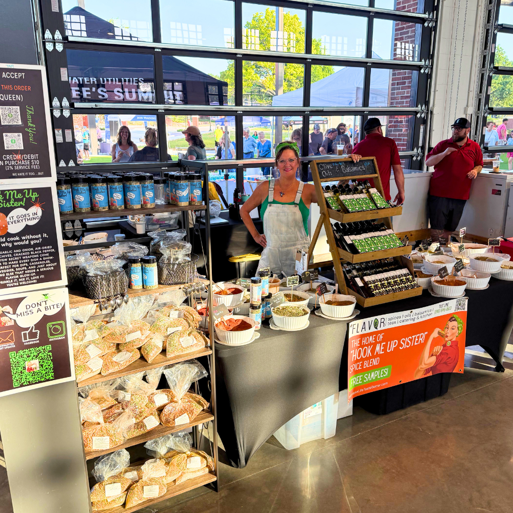 Flavor Kitchen booth at the Kansas City farmers market with spice blends, oils, and Hook Me Up Sister signage
